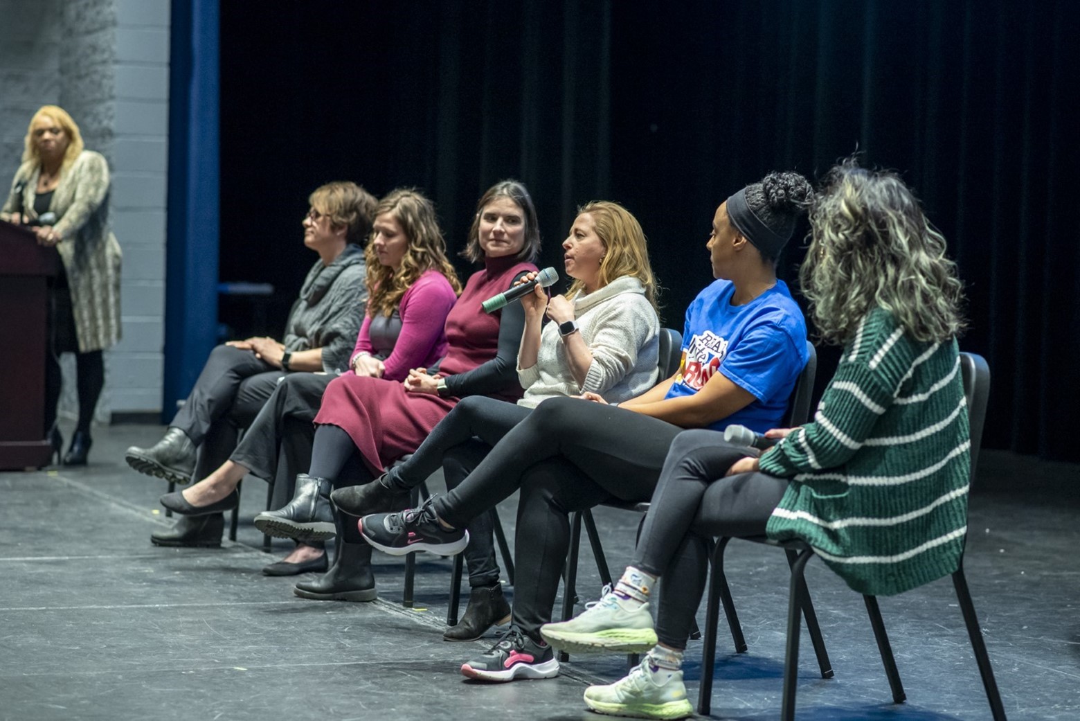 Women speaking on a panel on a stage. 