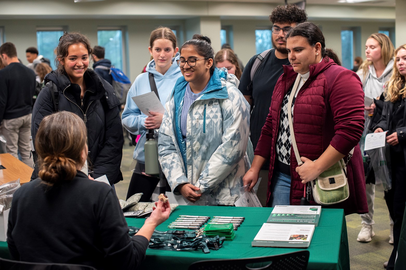 Male and female students stand around a booth listening to the financial literacy representative.