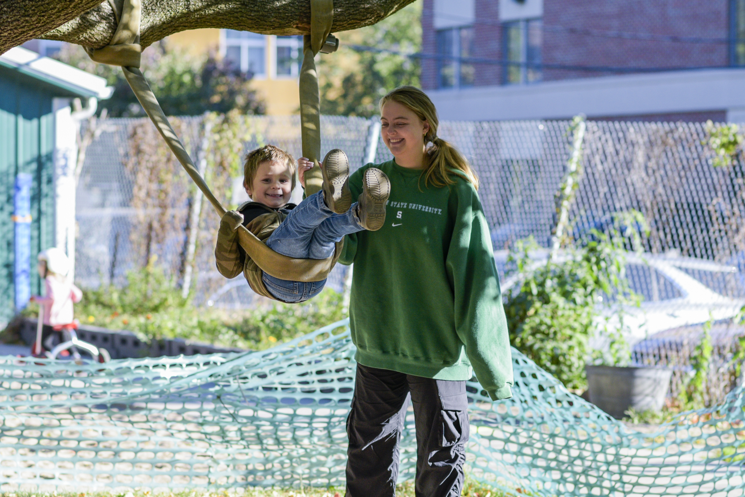 MSU undergrad pushes child on a swing.