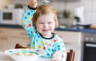 Fifteen month old eating from a plate.