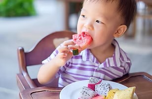 Eighteen month old eating from a plate.