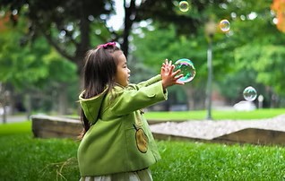 A three year old playing with bubbles.