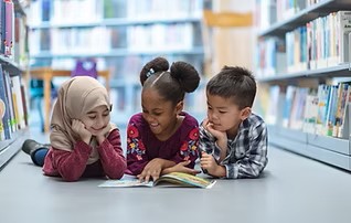 Four year olds reading a book together in a library.