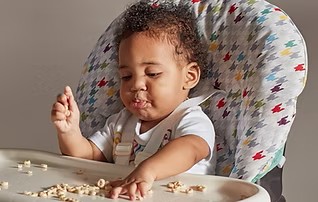 Nine month old eating cheerios in high chair.
