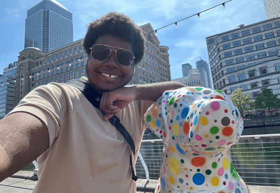 JMC student posing with a polka dot statue to a dog during a summer study abroad program.