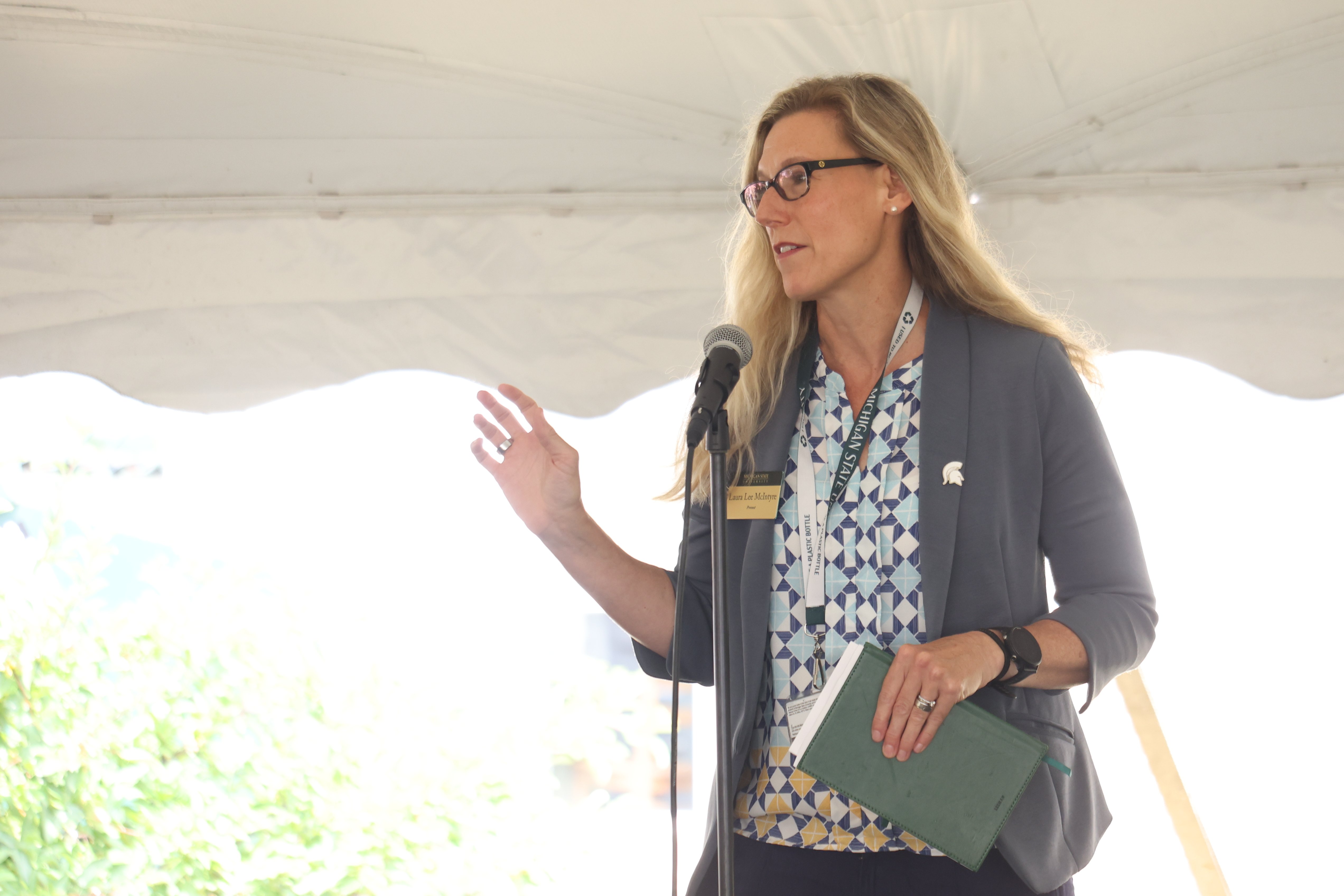 Provost Laura Lee McIntyre standing on a stage, speaking at a graduate student welcome event.