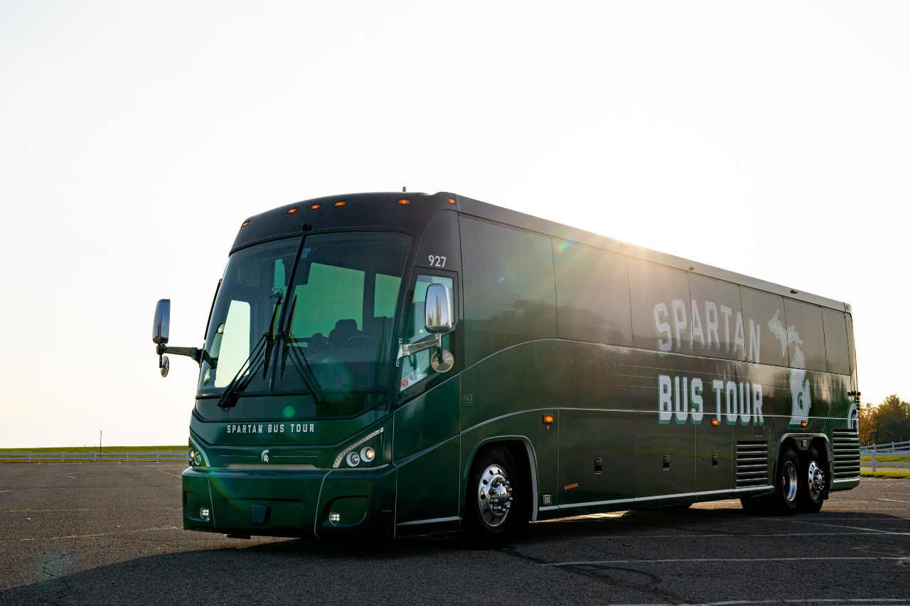 Passenger bus against the sunrise with green skin, says Spartan Bus Tour.