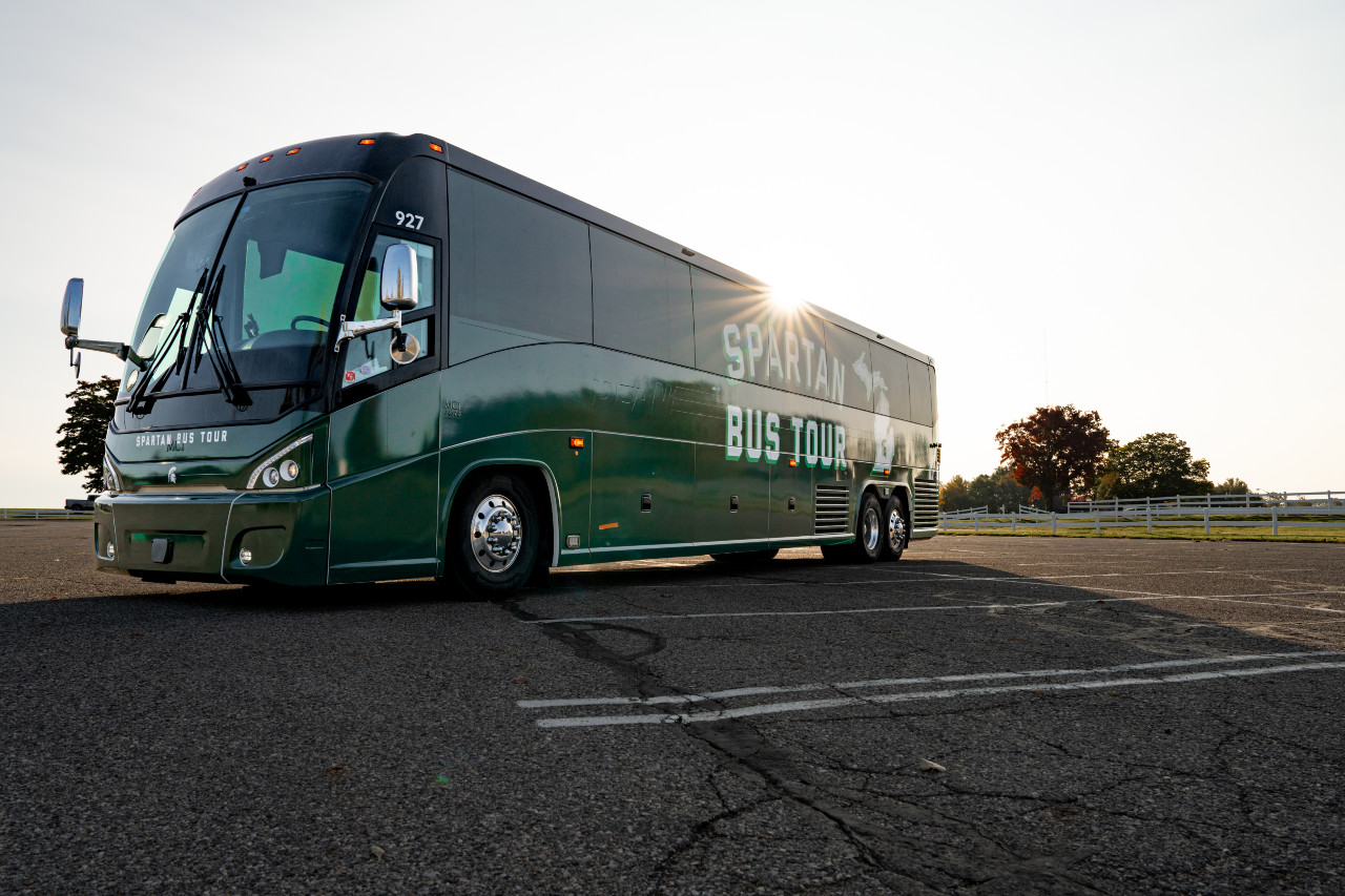 Passenger bus against the sunrise with green skin, says Spartan Bus Tour.