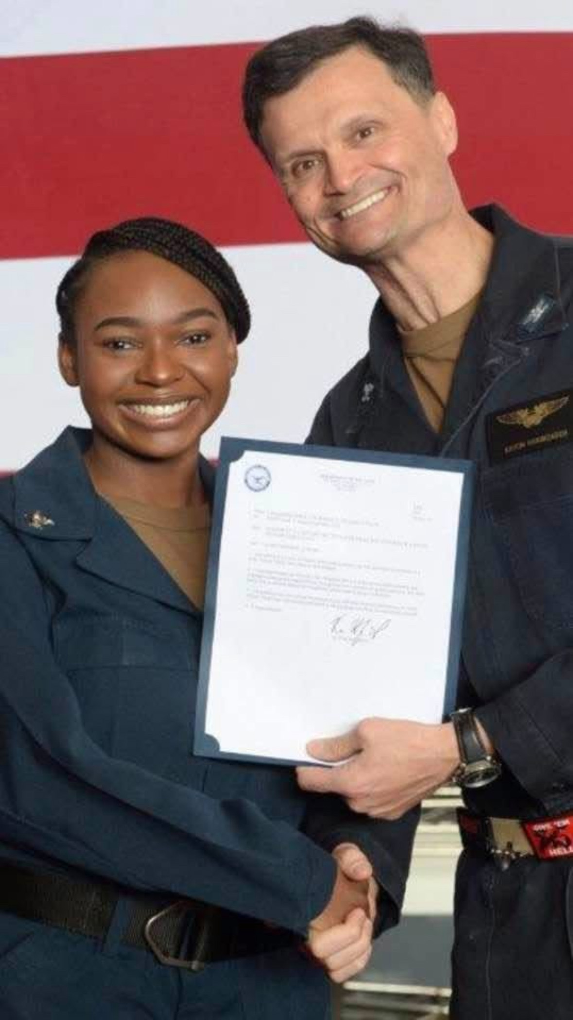 Ashley Cooper shakes hands with Rear Admiral Kavon Hakimzadeh as she is formally advanced to Second Class Petty Officer.