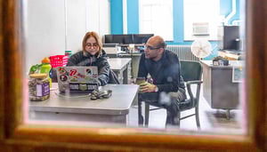A student and advisor sit together while looking at a laptop.