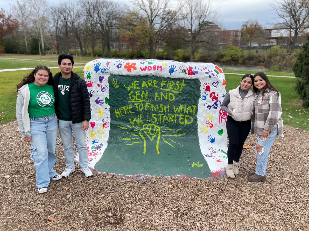 Students standing next to the rock painted for first-gen week.