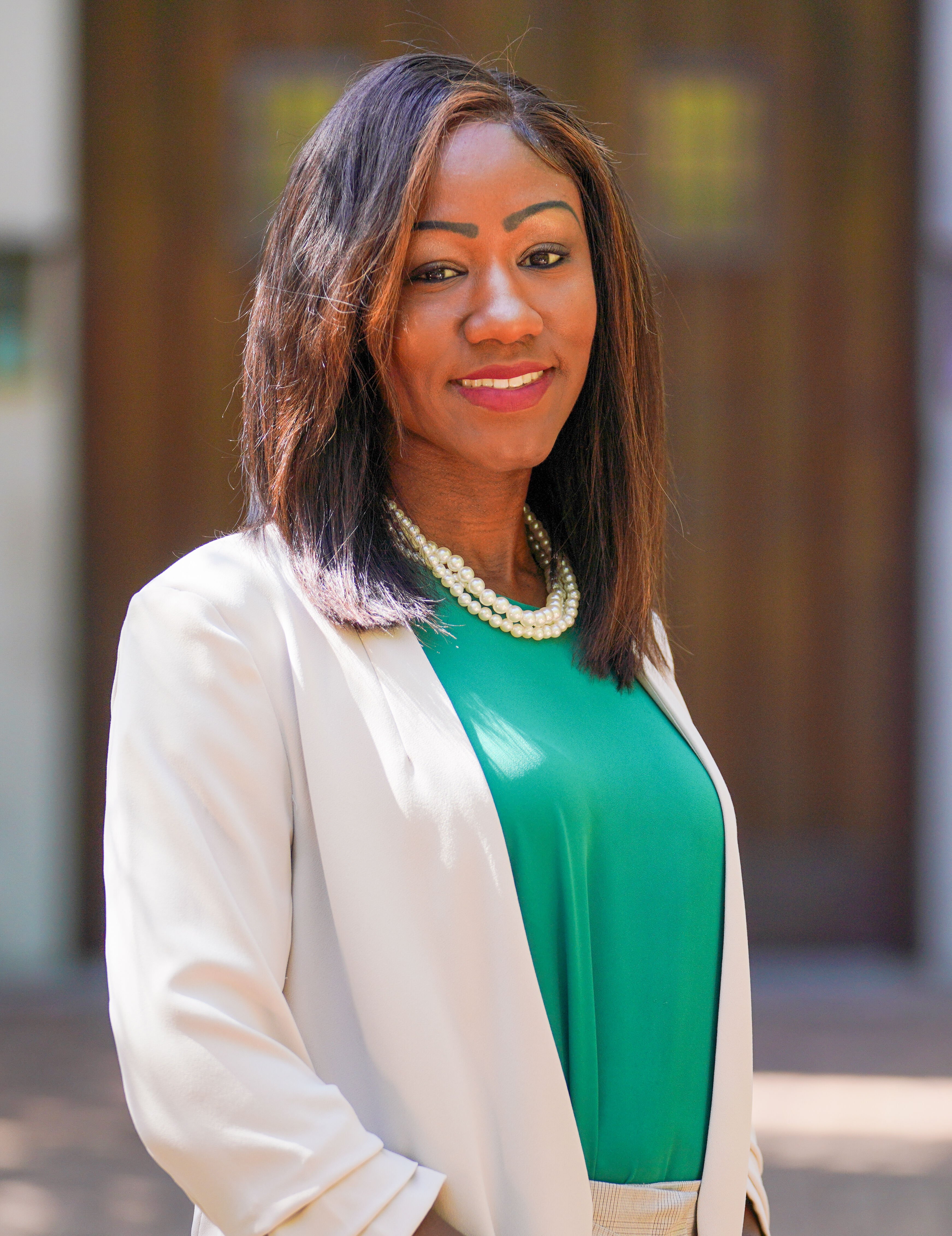 A photo of Dr Alexis Travis, outside on a sunny day, in front of Beaumont Tower on Michigan State University's Campus