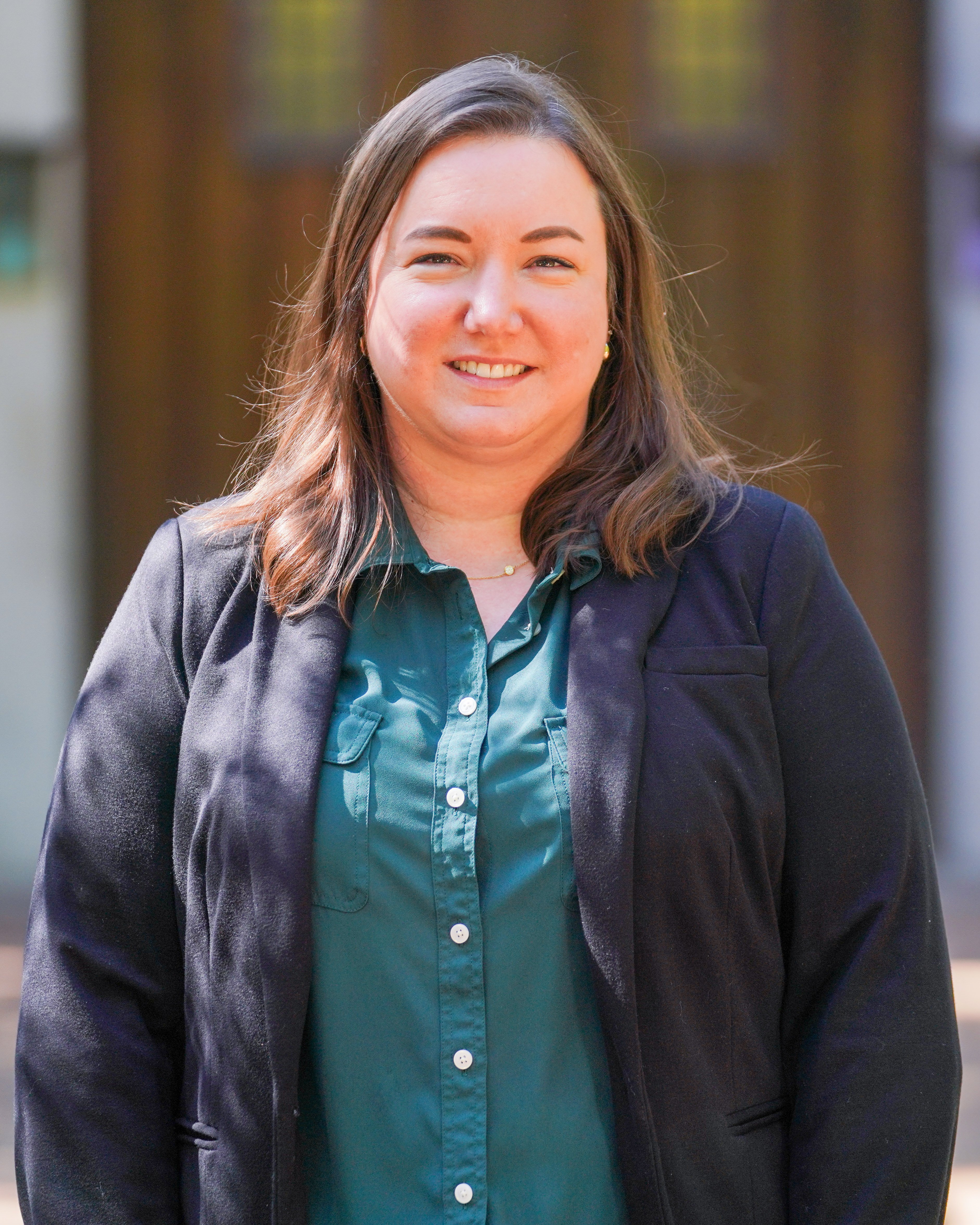 A photo of Elizabeth King, outside on a sunny day, in front of Beaumont Tower at Michigan State University