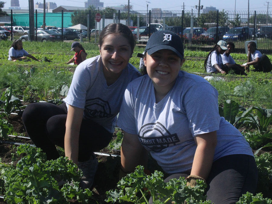 Two students sitting next to one another in a field of greens.