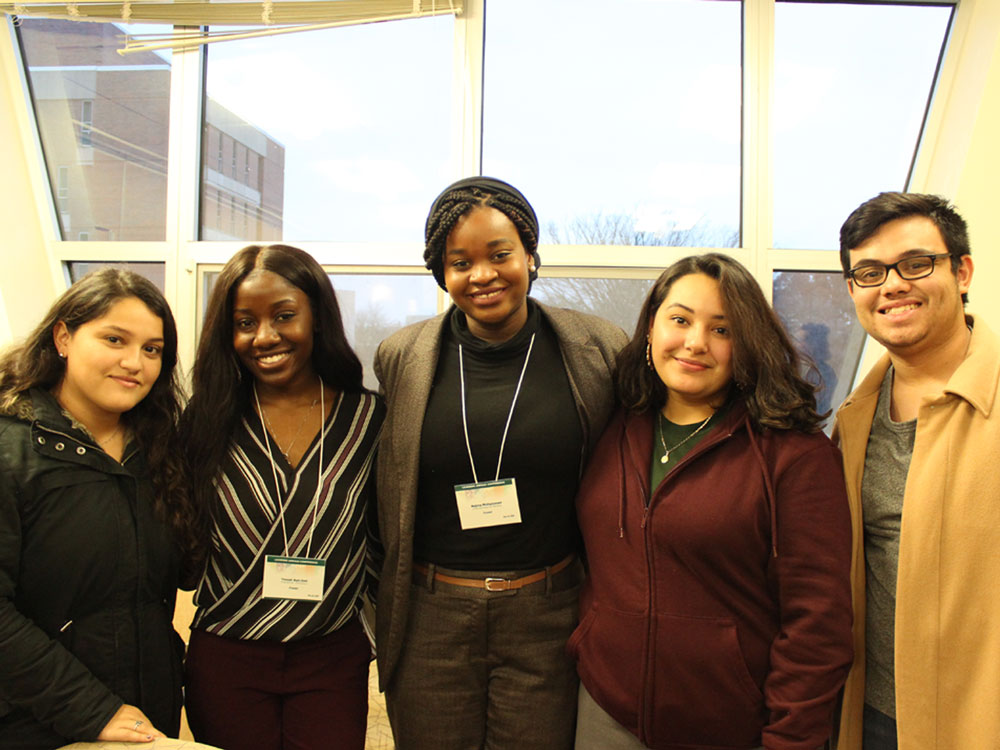 A group of students, some wearing badges, gathered together and smiling for a photo.