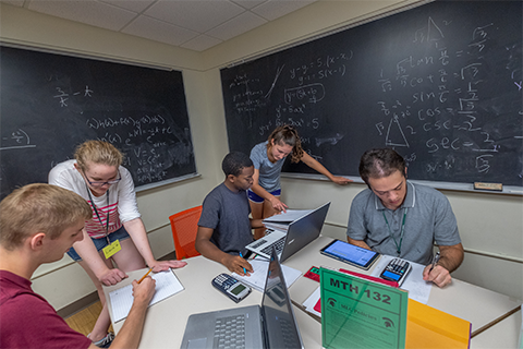 Students gathered around a computer in a discussion