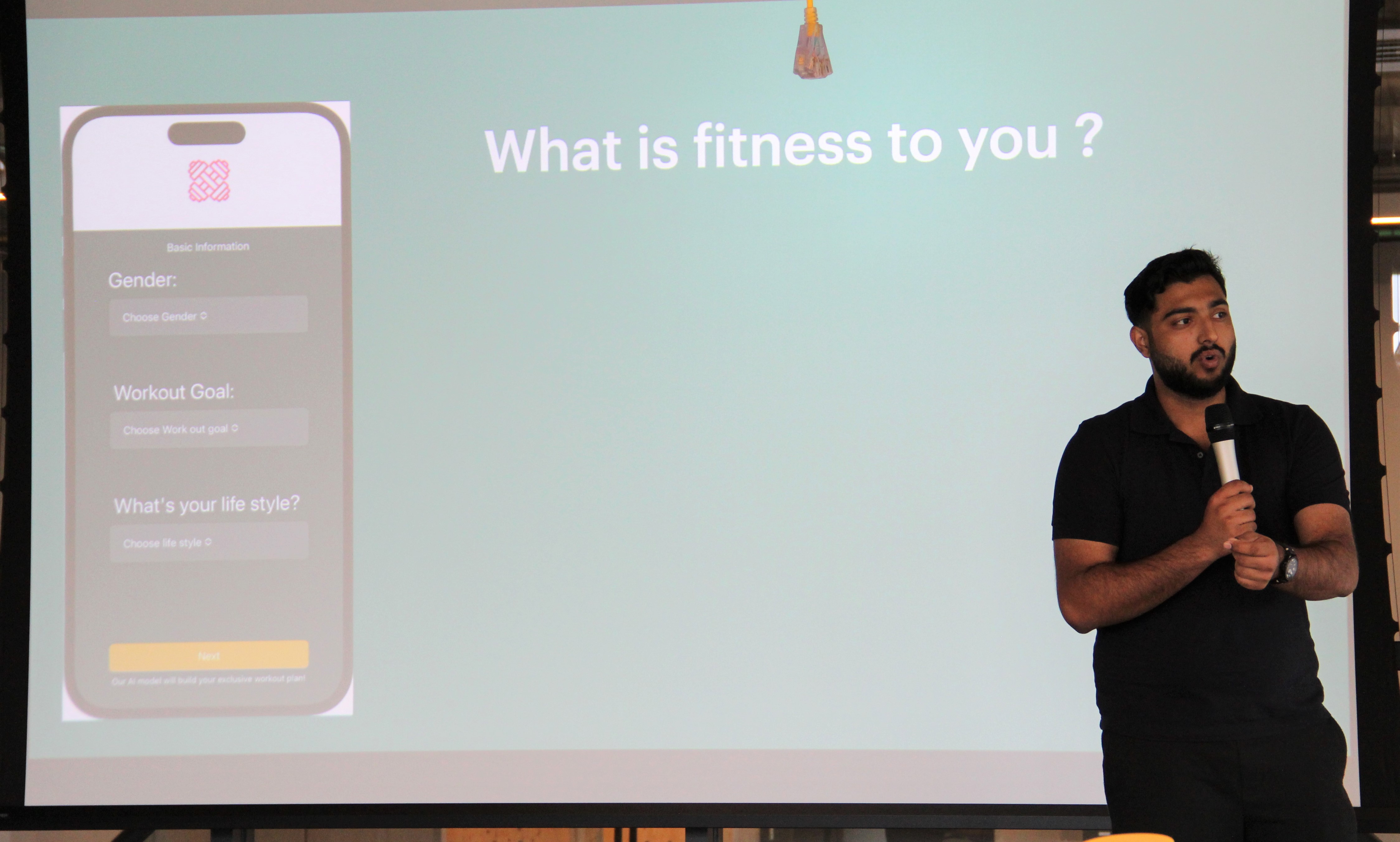 Student holding microphone in front of screen and presenting