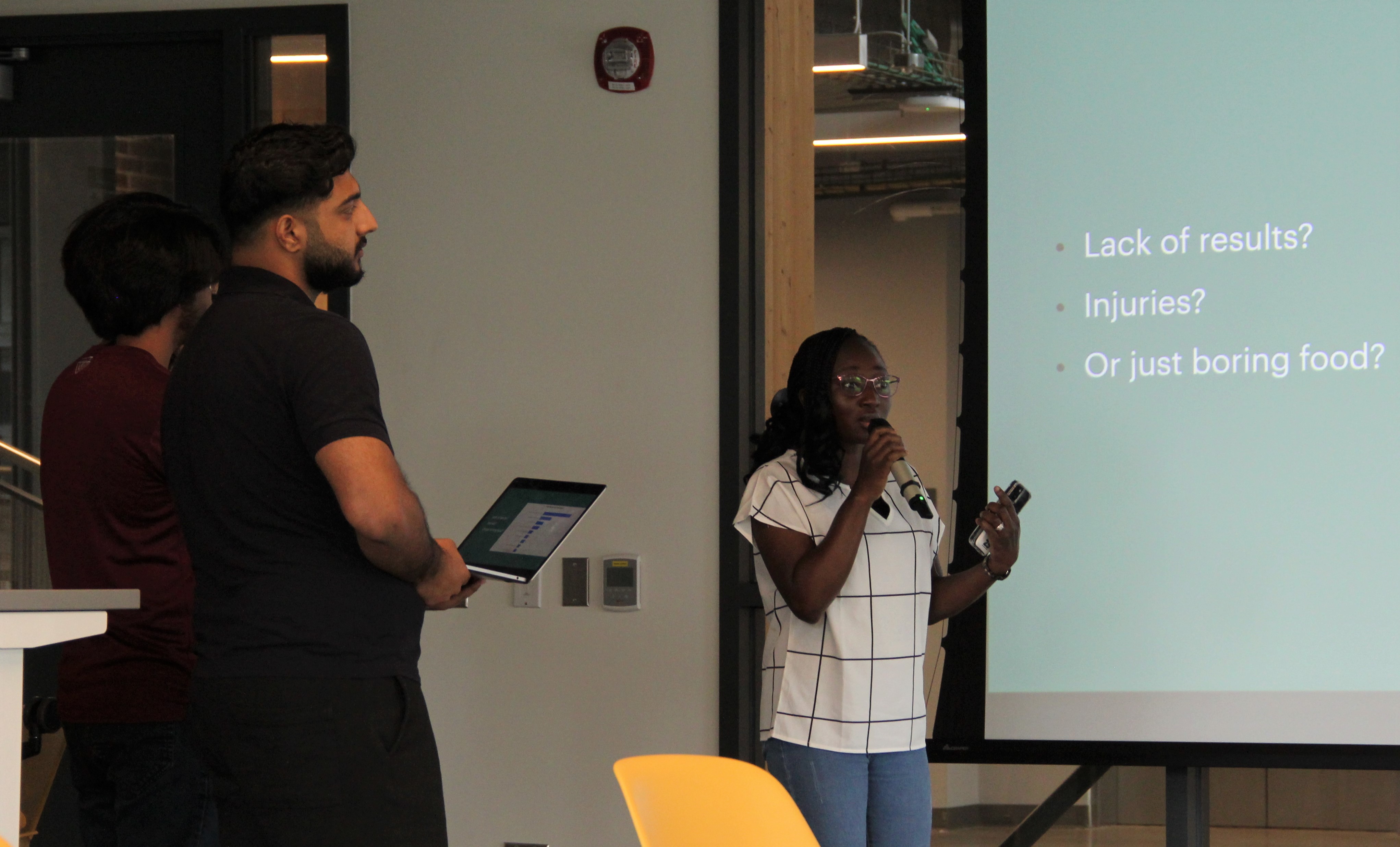 Student holding microphone in front of screen and presenting