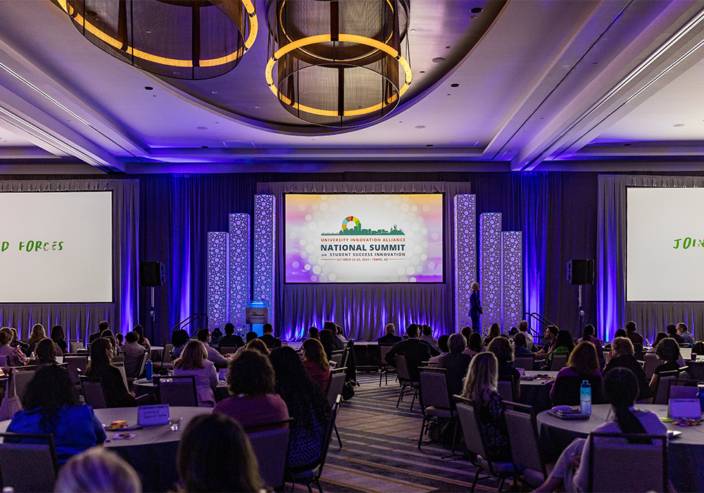 Main stage with a presentation screen dropped down and displaying the UIA Summit information in a banquet hall