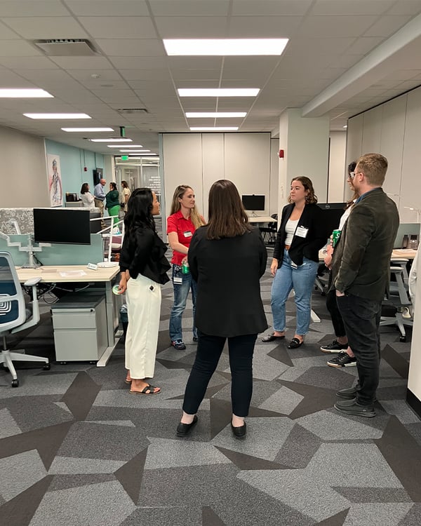 Several people are spread across an open workspace socializing during the CTLI Open House.