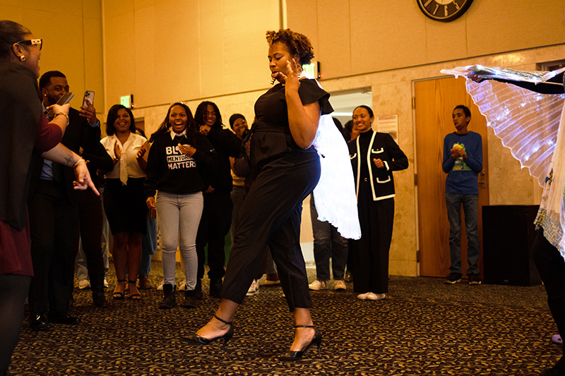 A person in the middle of dancing, while surrounded on one side with onlookers..
