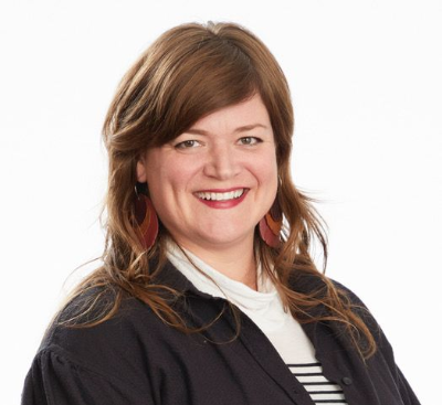 Portrait of Jennifer Lee Johnson wearing a dark jacket, with long red hair down to the shoulders.