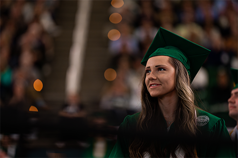Student in cap and gown standing at graduating ceremony