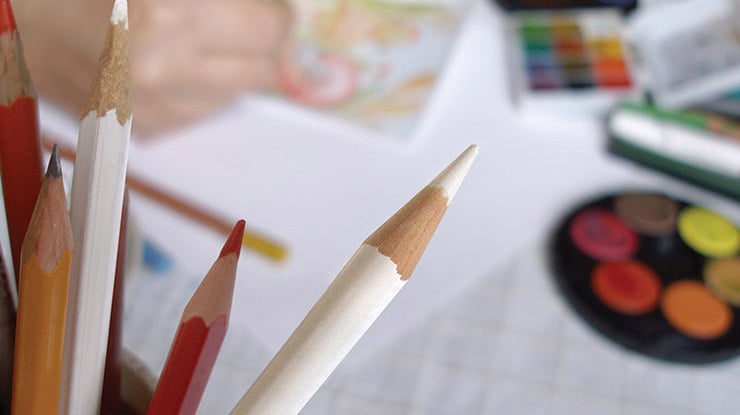 Some art education degree supplies ? red and white colored pencils are in sharp focus by multicolored art supplies.