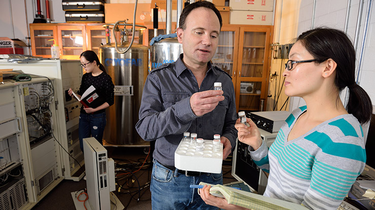A professor and two chemistry majors examine chemicals and lab equipment needed for learning.