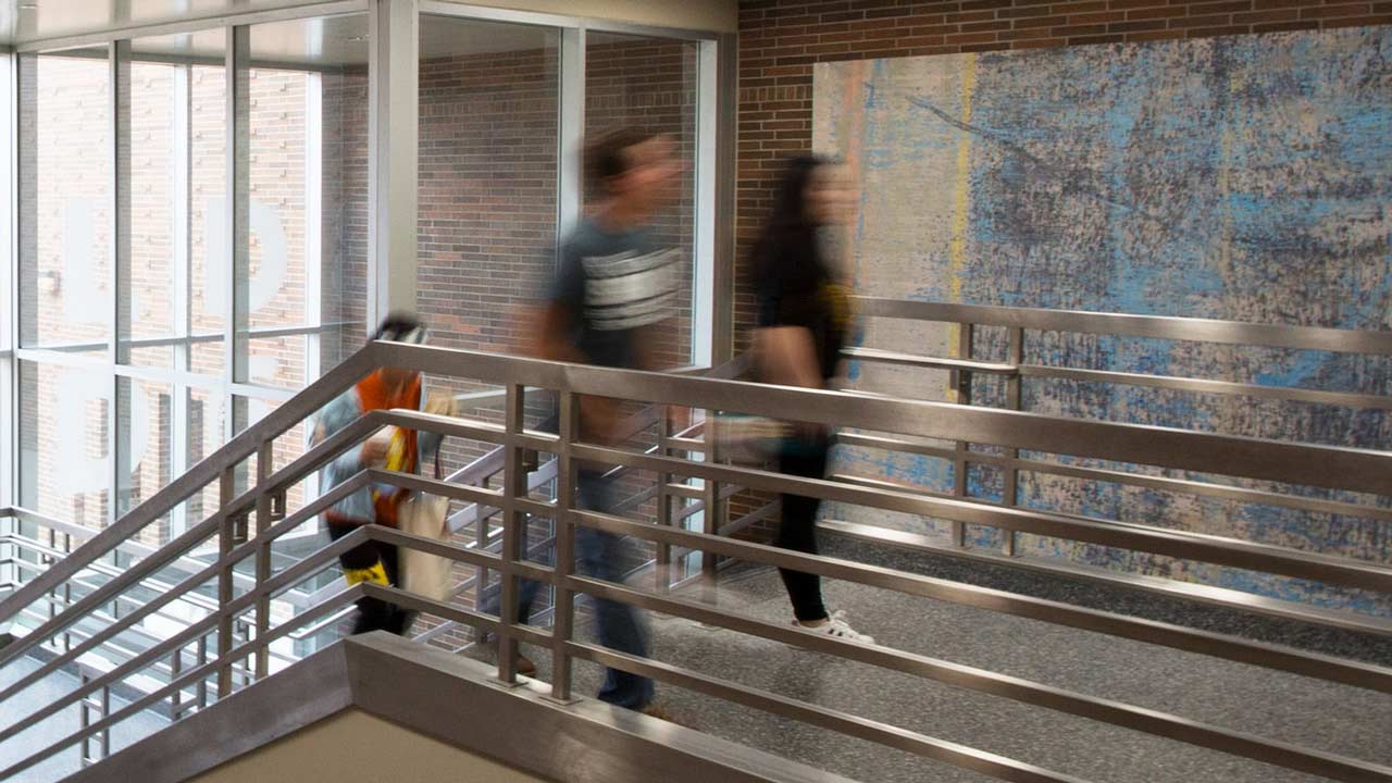 Students pursuing a human resource management degree walk up a metal staircase in one of MSU?s campus buildings.