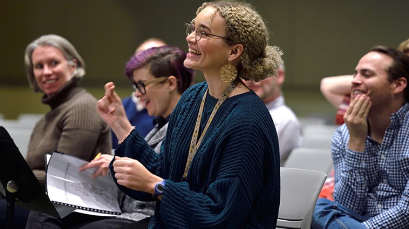 A student in the music composition degree program at MSU composes at a music stand while her classmates listen in the background.