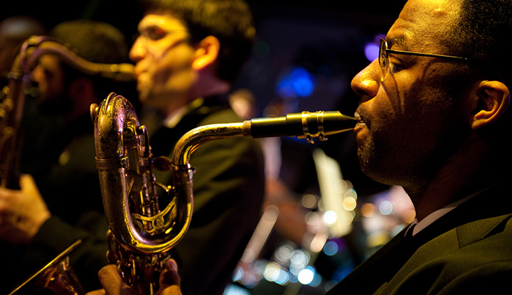 A music major playing a saxophone in a horn section at Michigan State University.