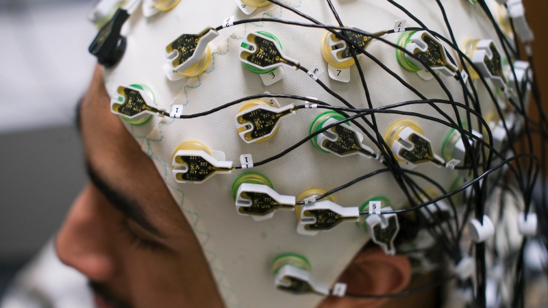 A smiling student working on a psychology degree wearing a headpiece.