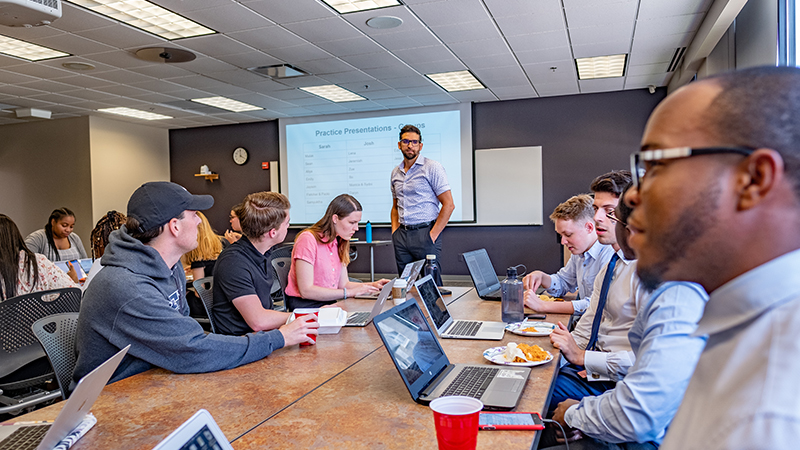 Students discuss presentation ideas with an instructor in a classroom, building communication and teaching skills in a public affairs major.