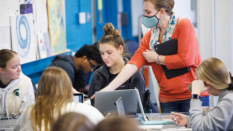 Students collaborate on laptops as an instructor guides discussion in class, reflecting MSU’s science technology and society focus on people and ideas.