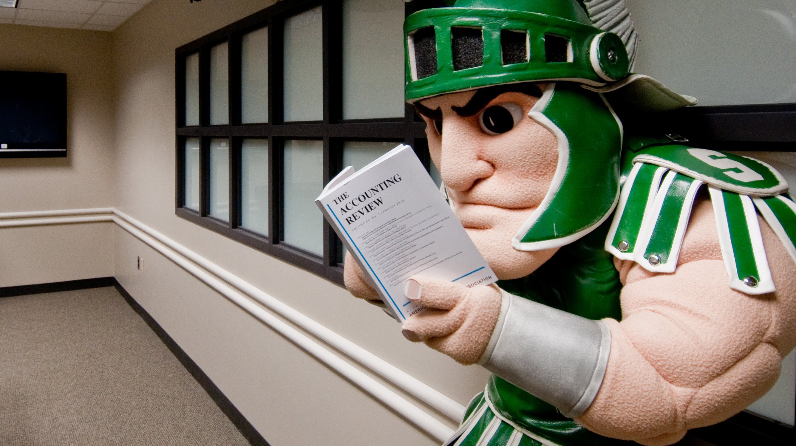Sparty (MSU mascot) studies a guide labeled The Accounting review.