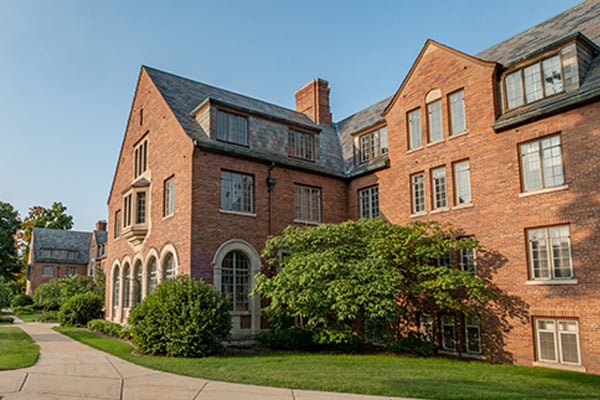 Red brick academic building with arched windows and a landscaped walkway on a Michigan State University's campus.