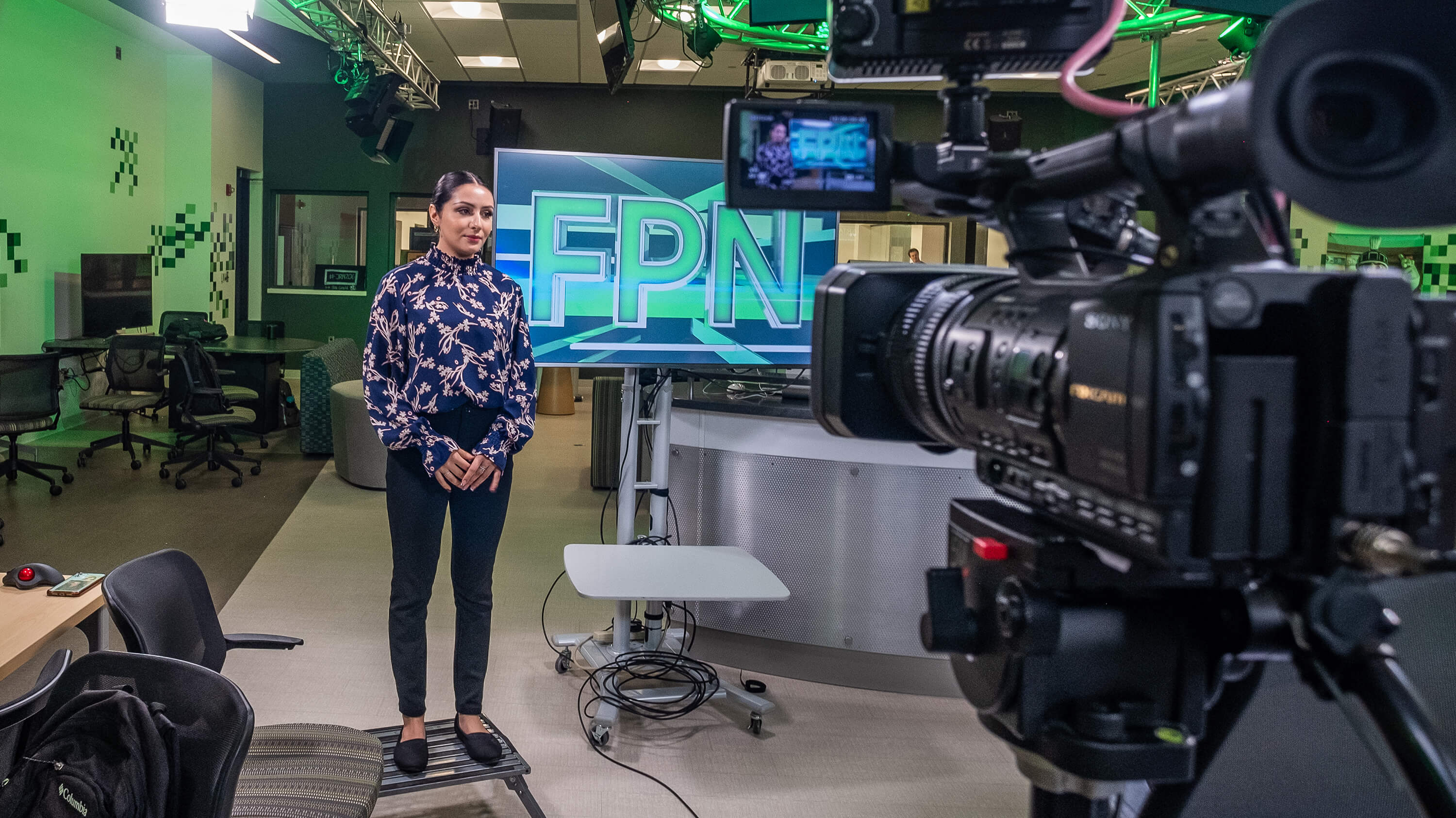 A student new anchor reporting in front of a camera in the MSU Focal Point News studio.