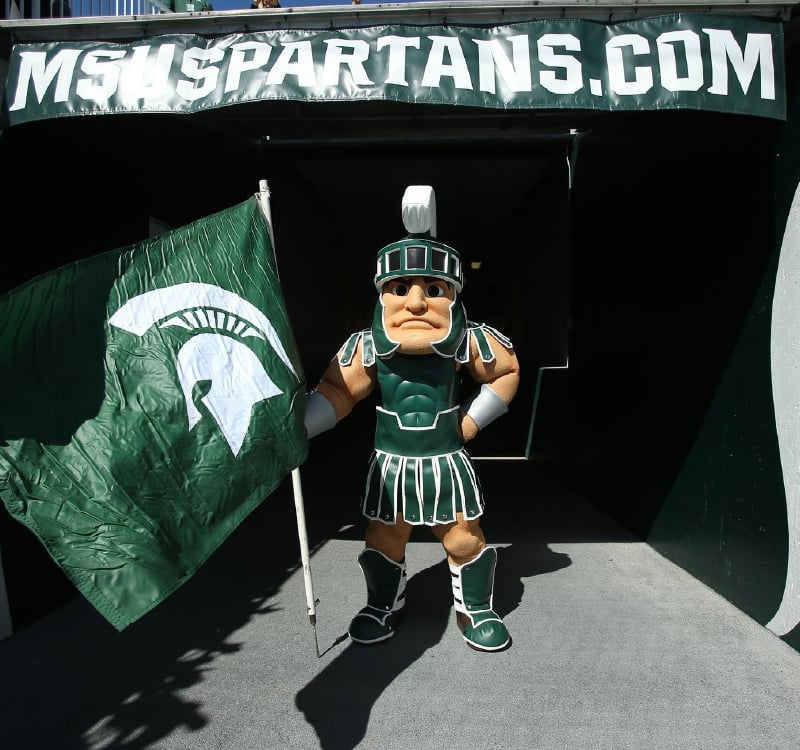 Sparty is holding a flag, at the entrance of the Spartan Stadium.
