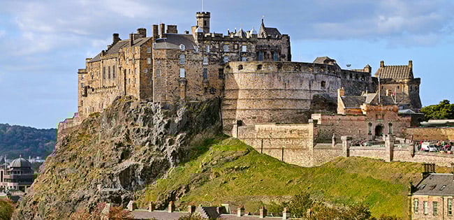Edinburgh Castle stands atop Castle Rock in Scotland, overlooking the city with its historic stone walls and medieval architecture.