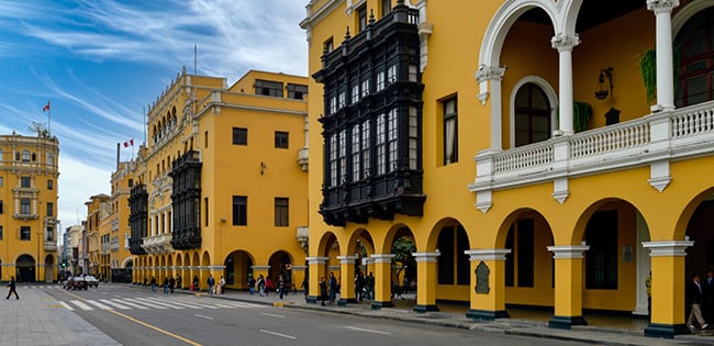 Colonial architecture painted in golden yellow lines a street in Lima, Peru, featuring traditional balconies and arched walkways.