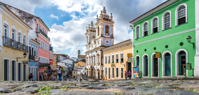 Colorful colonial buildings and a baroque church along a cobblestone street in Salvador, Brazil.