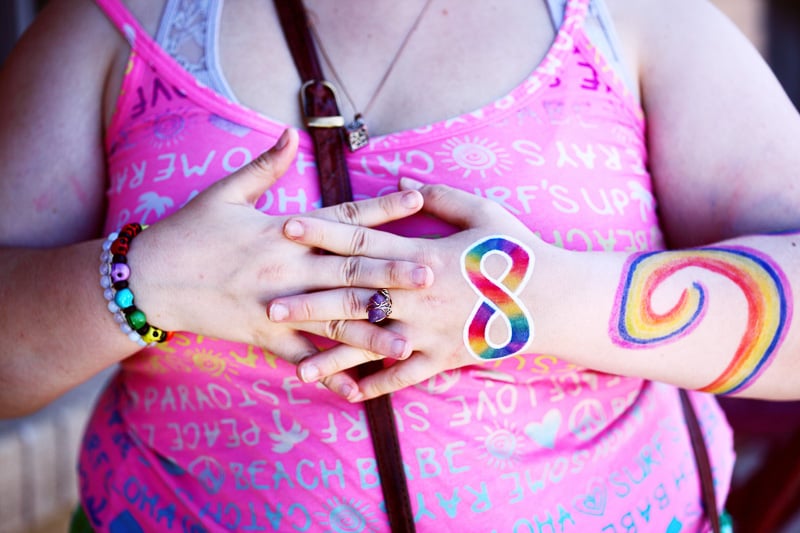 Individual with crossed hands over their chest. Painted on their hand is an infinity sign, a symbol for autism. 