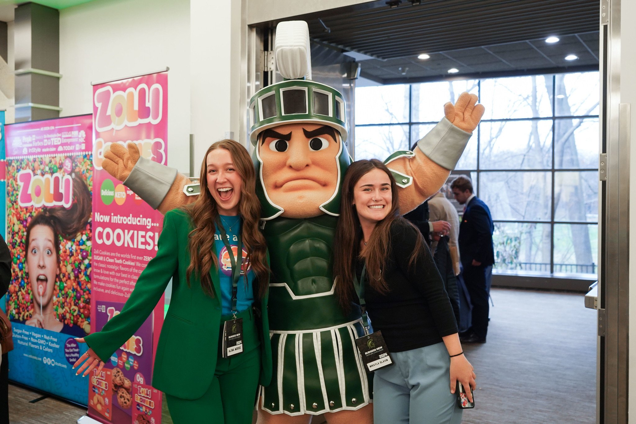 Sparty mascot standing with 2 students.