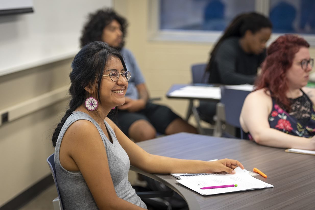 Student smiles in a classroom with other students.