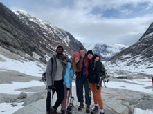 A group of women and male students with snow and mountains behind them.