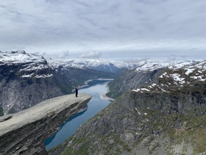 Carrie on a rock overhang above a lake and mountains.