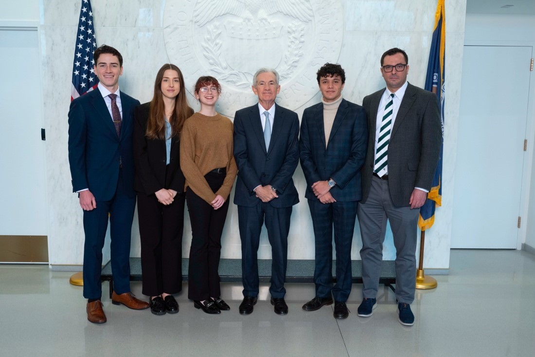 Students and professor stand with fed challenge chairperson.