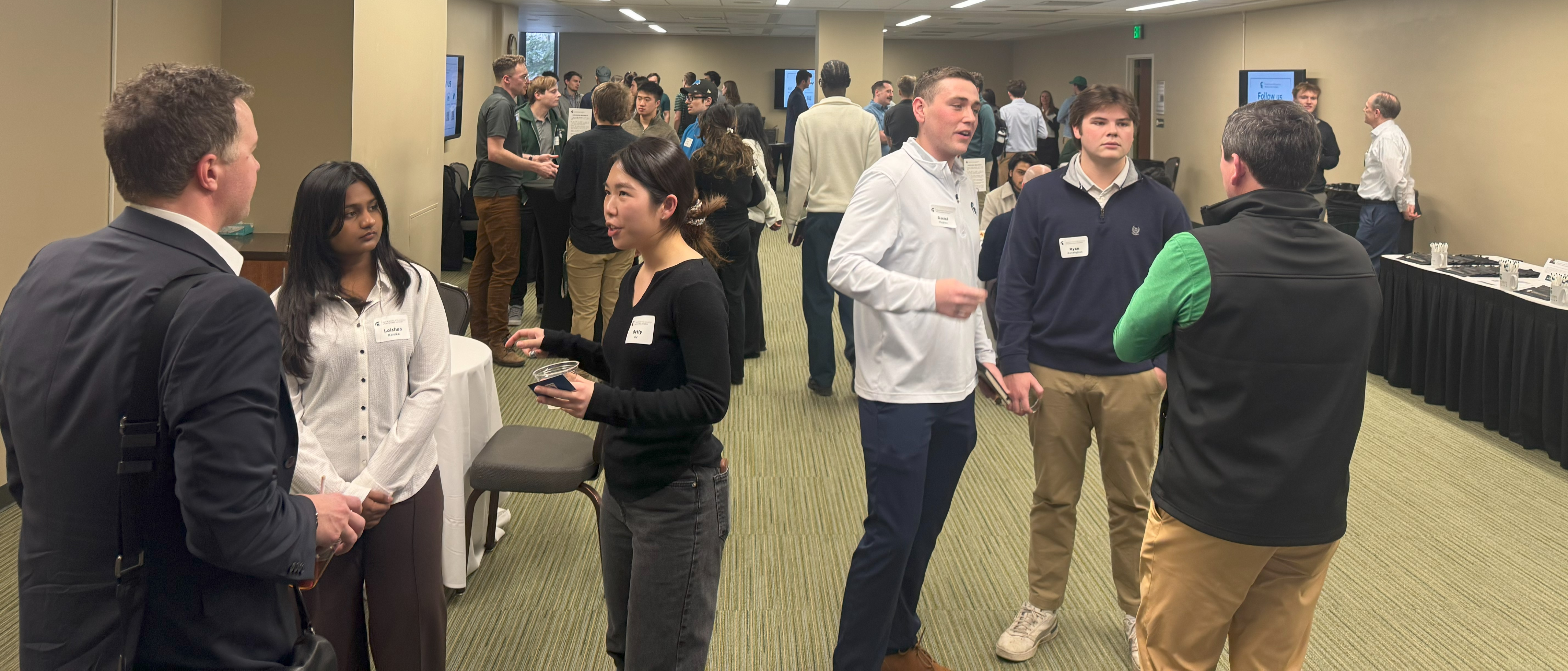 A conference room filled with alumni and students talking to each other.
