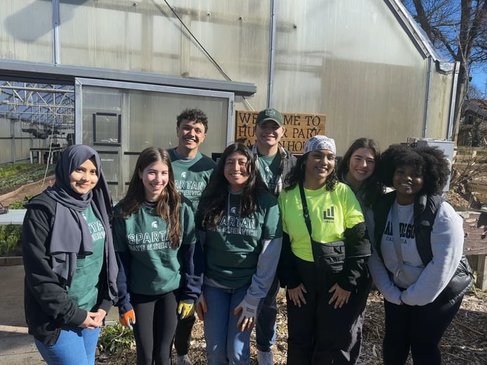 Group of student volunteers in front of greenhouse.